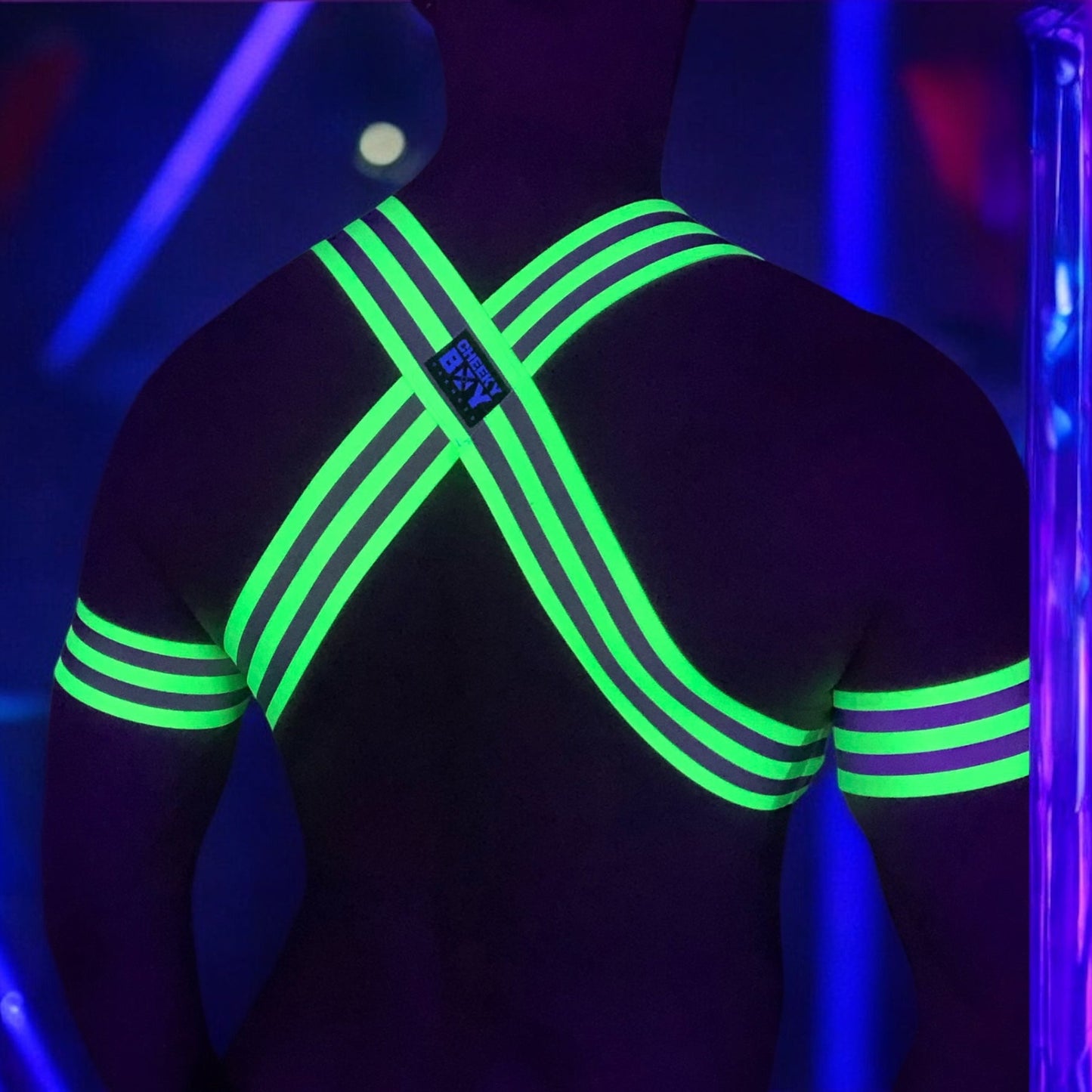 Made-to-measure men’s elastic chest harness in high-visibility neon yellow with reflective detailing, glowing under blacklight. The design features double shoulder and chest straps joined by circular O-rings, with optional matching jockstrap and thigh bands—ideal for clubwear, festivals, or fetish fashion.