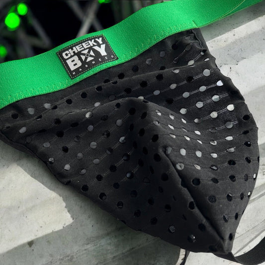 Men’s black mesh jockstrap with green elastic waistband, featuring a Cheeky Boy Harness black and white logo at the centre front, and black rear straps.