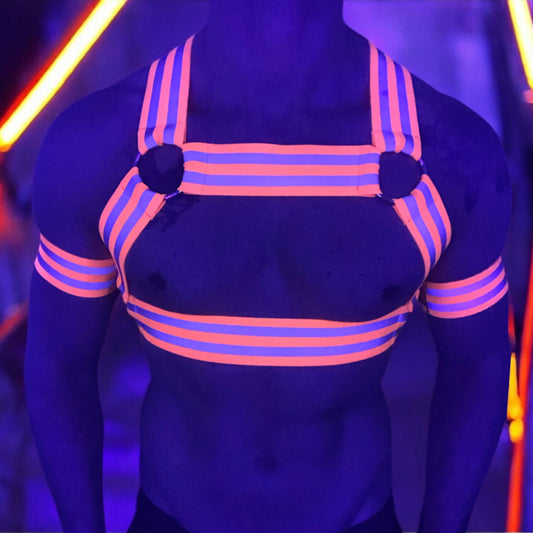 Made-to-measure men’s elastic chest harness in high-visibility neon orange with reflective detailing, glowing under blacklight. The design features double shoulder and chest straps joined by circular O-rings, with optional matching jockstrap and thigh bands—ideal for clubwear, festivals, or fetish fashion.