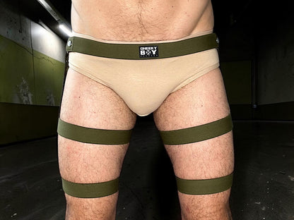 Men’s army green thigh strap shorts worn over beige underwear without the optional pouch
