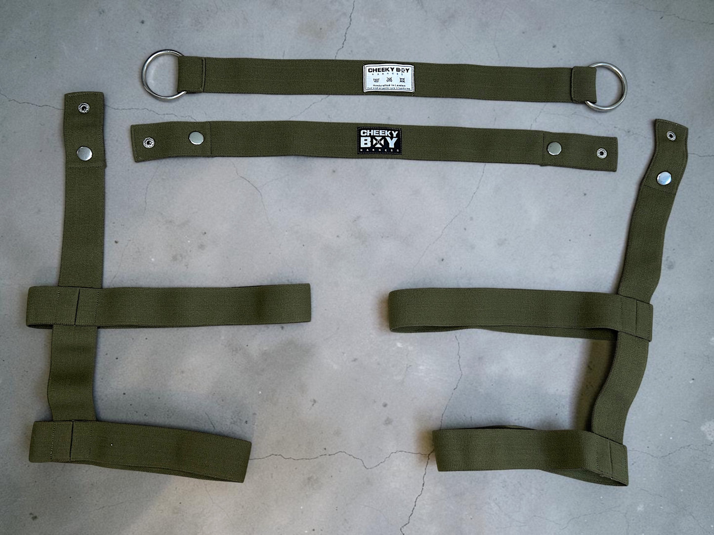 Army green harness shorts laid flat to show the waistband, thigh bands and connecting straps
