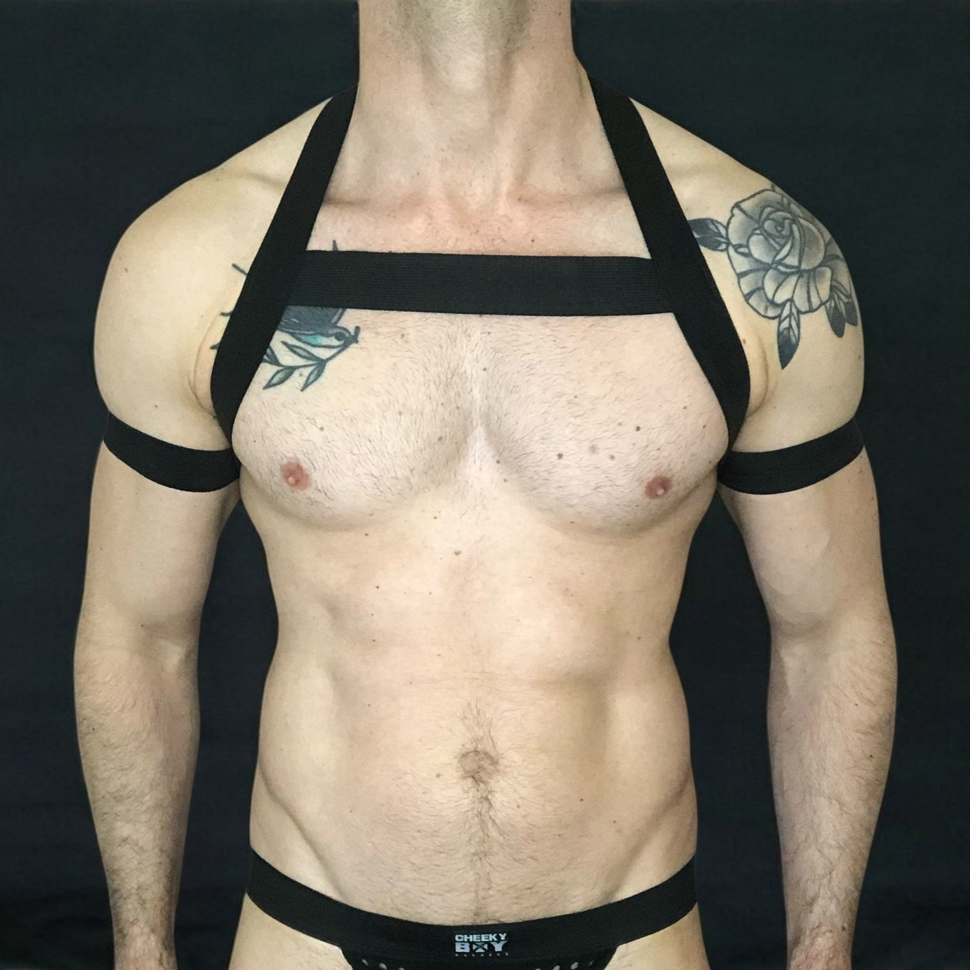 Model wearing a custom-made made elastic chest harness and black mesh jockstrap by Cheeky Boy Harness. Made-to-measure men's festival and clubwear set designed for pride, circuit parties, and dance events
