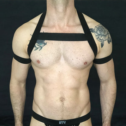 Model wearing a custom-made made elastic chest harness and black mesh jockstrap by Cheeky Boy Harness. Made-to-measure men's festival and clubwear set designed for pride, circuit parties, and dance events