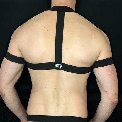 Model wearing a custom-made made elastic chest harness and black mesh jockstrap by Cheeky Boy Harness. Made-to-measure men's festival and clubwear set designed for pride, circuit parties, and dance events