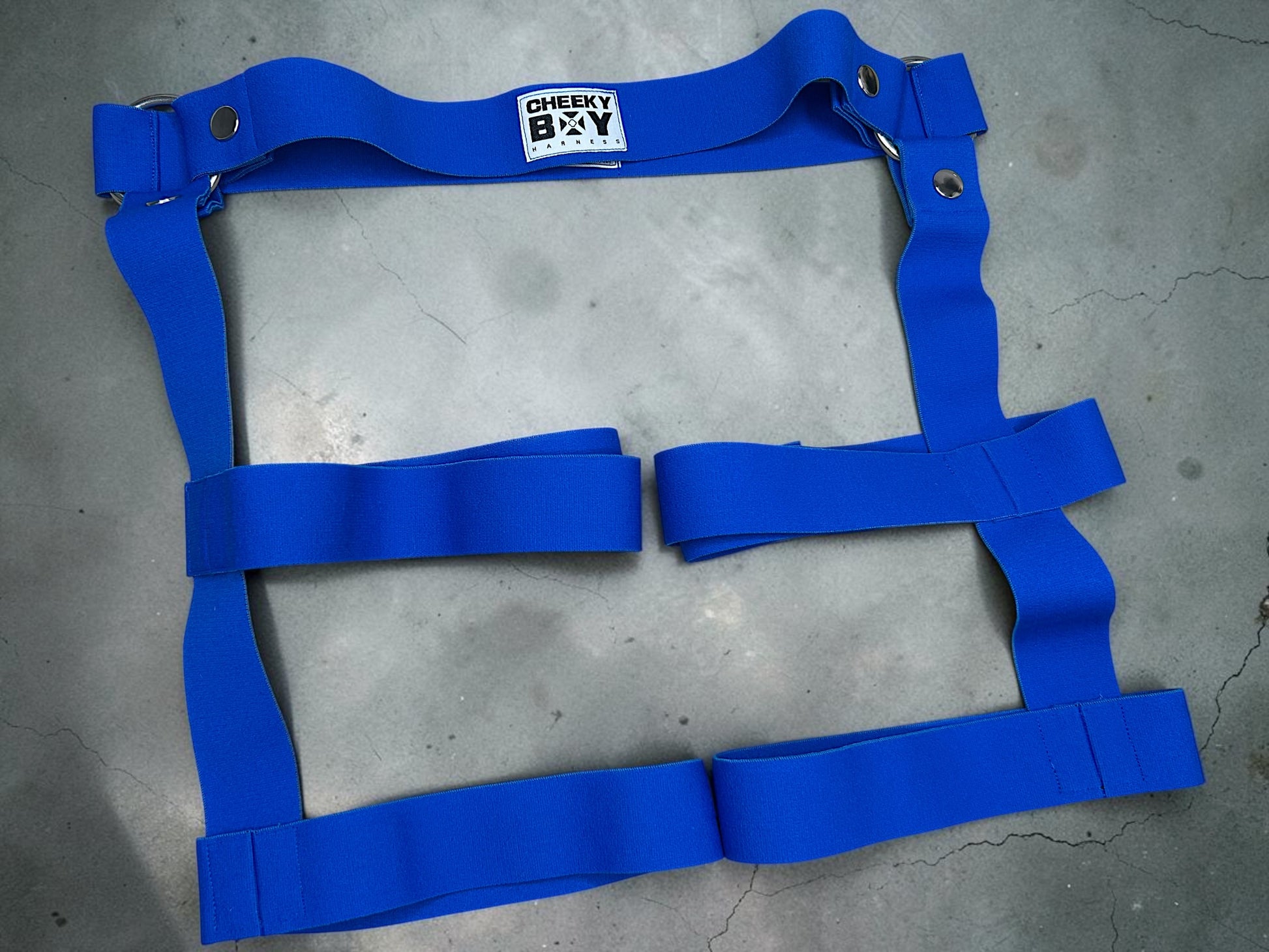 Royal blue elastic harness shorts laid flat to show the complete thigh strap design
