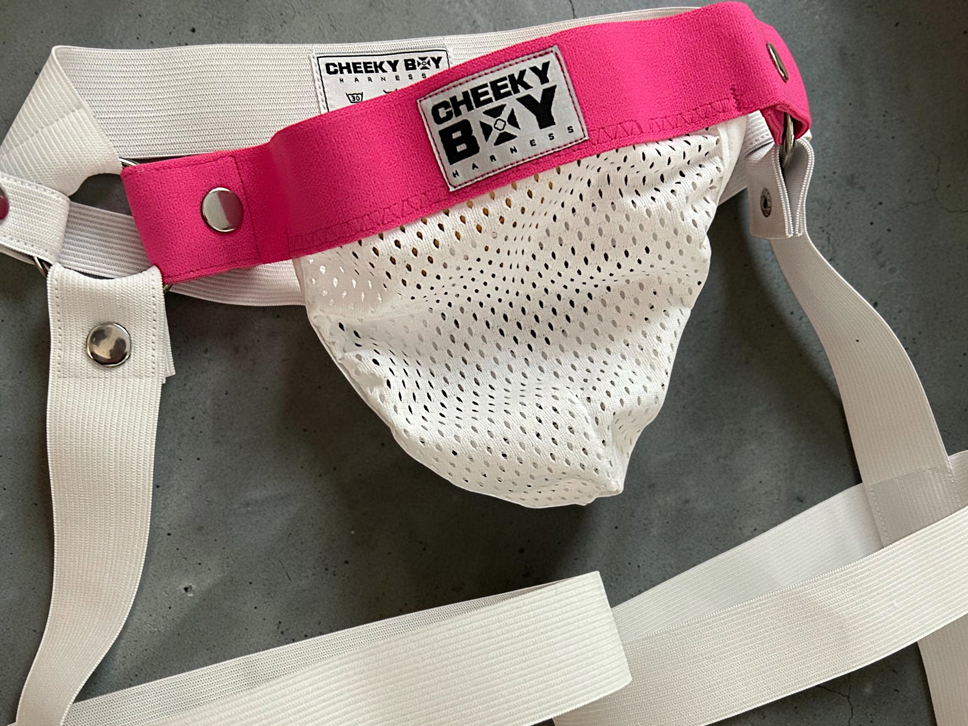 Close view of hot pink waistband with white mesh clip-on jockstrap pouch
