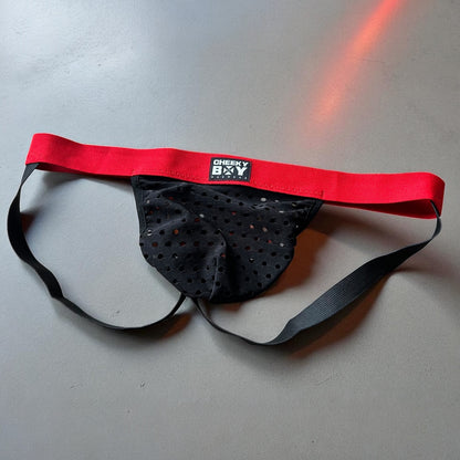 Men’s black mesh Christmas jockstrap with red elastic waistband, featuring a Cheeky Boy Harness black and brand logo at the centre.
