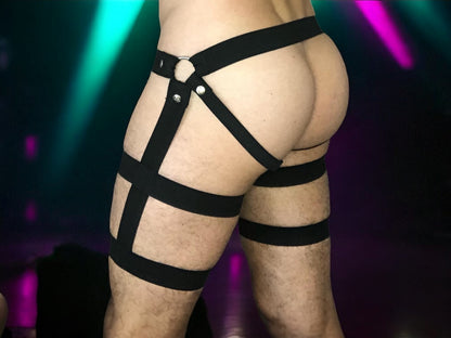 Rear three-quarter view of black men’s harness shorts showing the geometric strap design

