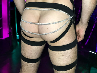 Rear view of black elastic harness shorts worn over beige underwear in club lighting
