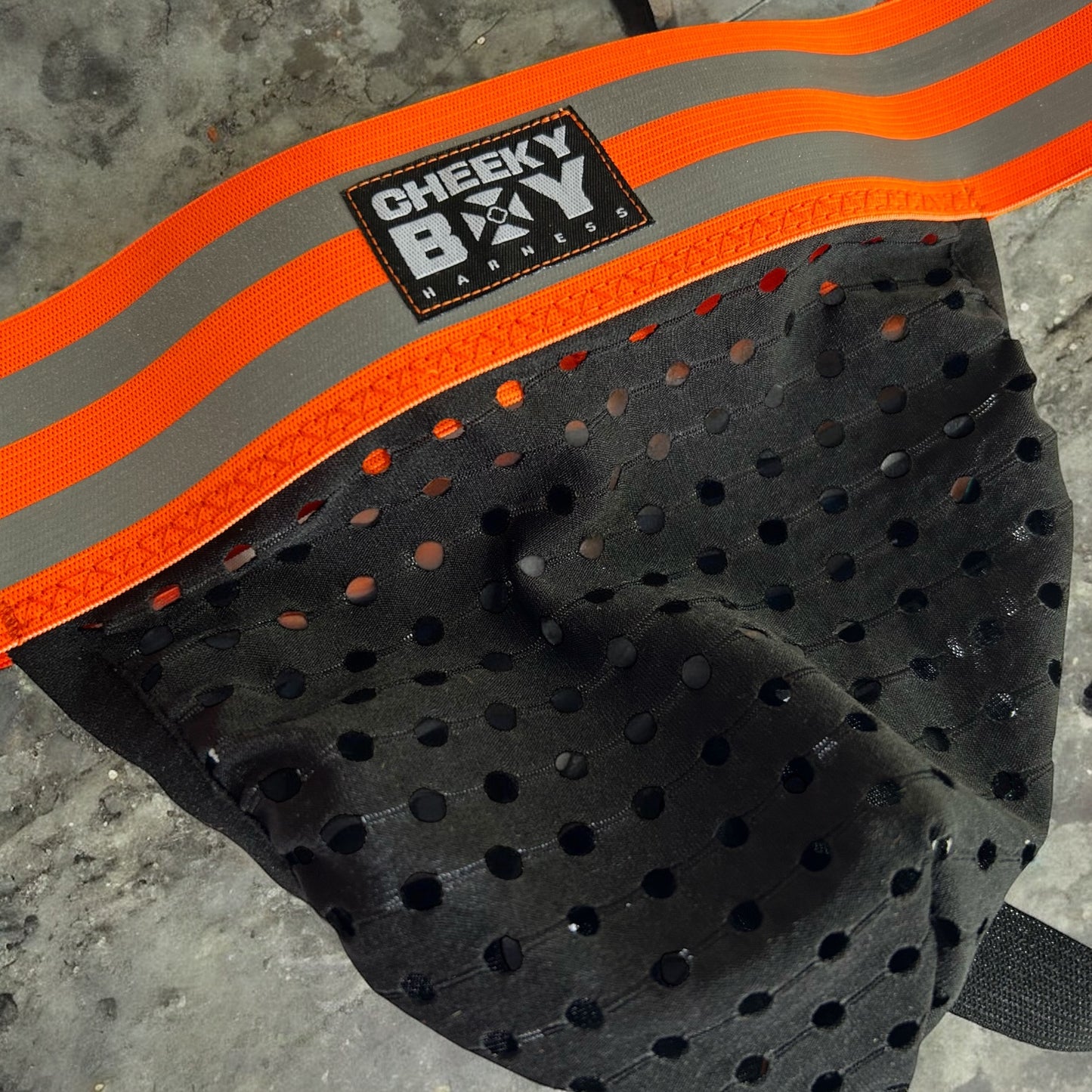 Black mesh pouch jockstrap with a wide hi-vis neon orange reflective waistband, branded Cheeky Boy Harness.