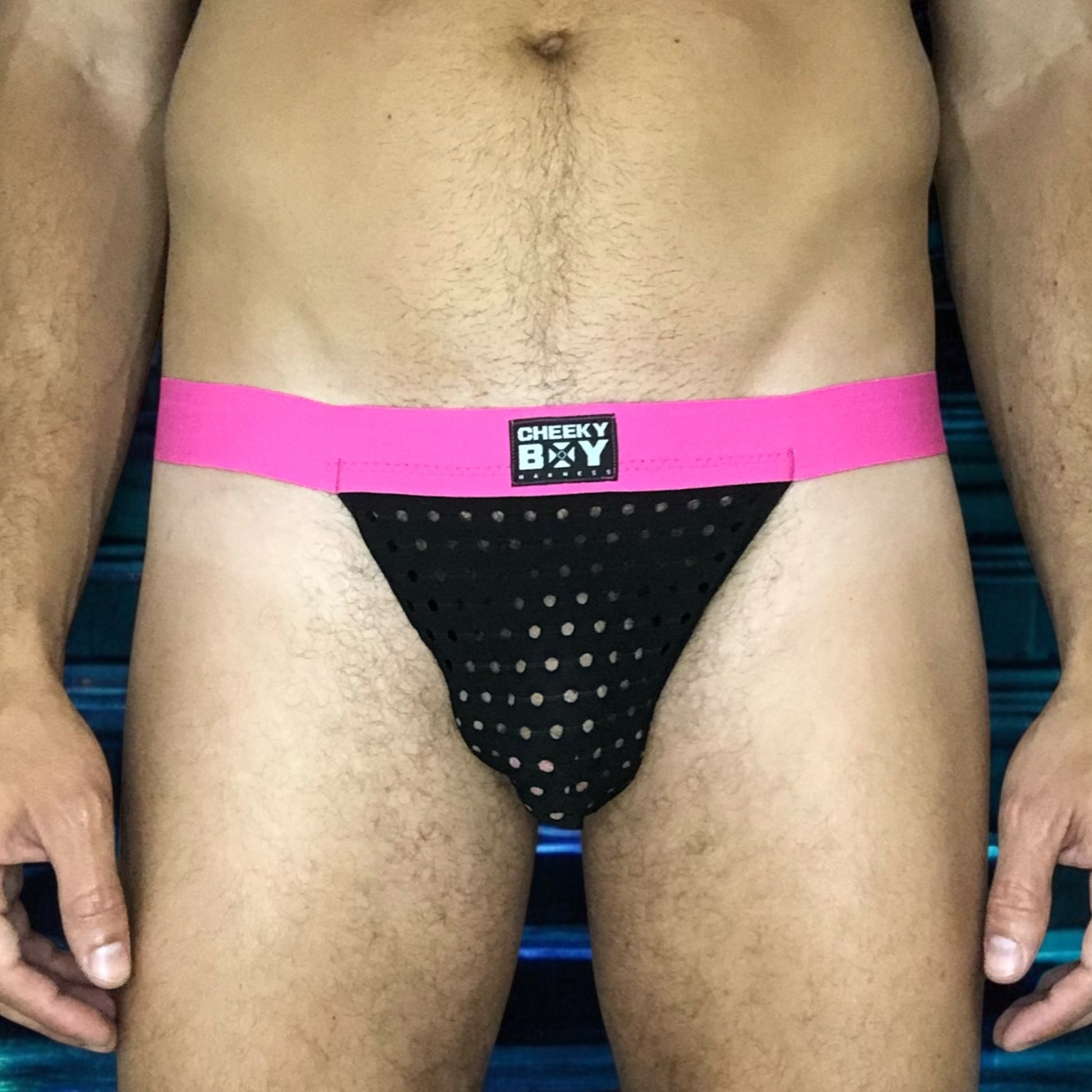Model wearing a custom-made hot pink black mesh jockstrap by Cheeky Boy Harness. Made-to-measure men's festival and clubwear set designed for pride, circuit parties, and dance events