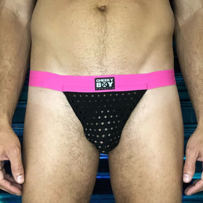 Model wearing a custom-made hot pink black mesh jockstrap by Cheeky Boy Harness. Made-to-measure men's festival and clubwear set designed for pride, circuit parties, and dance events