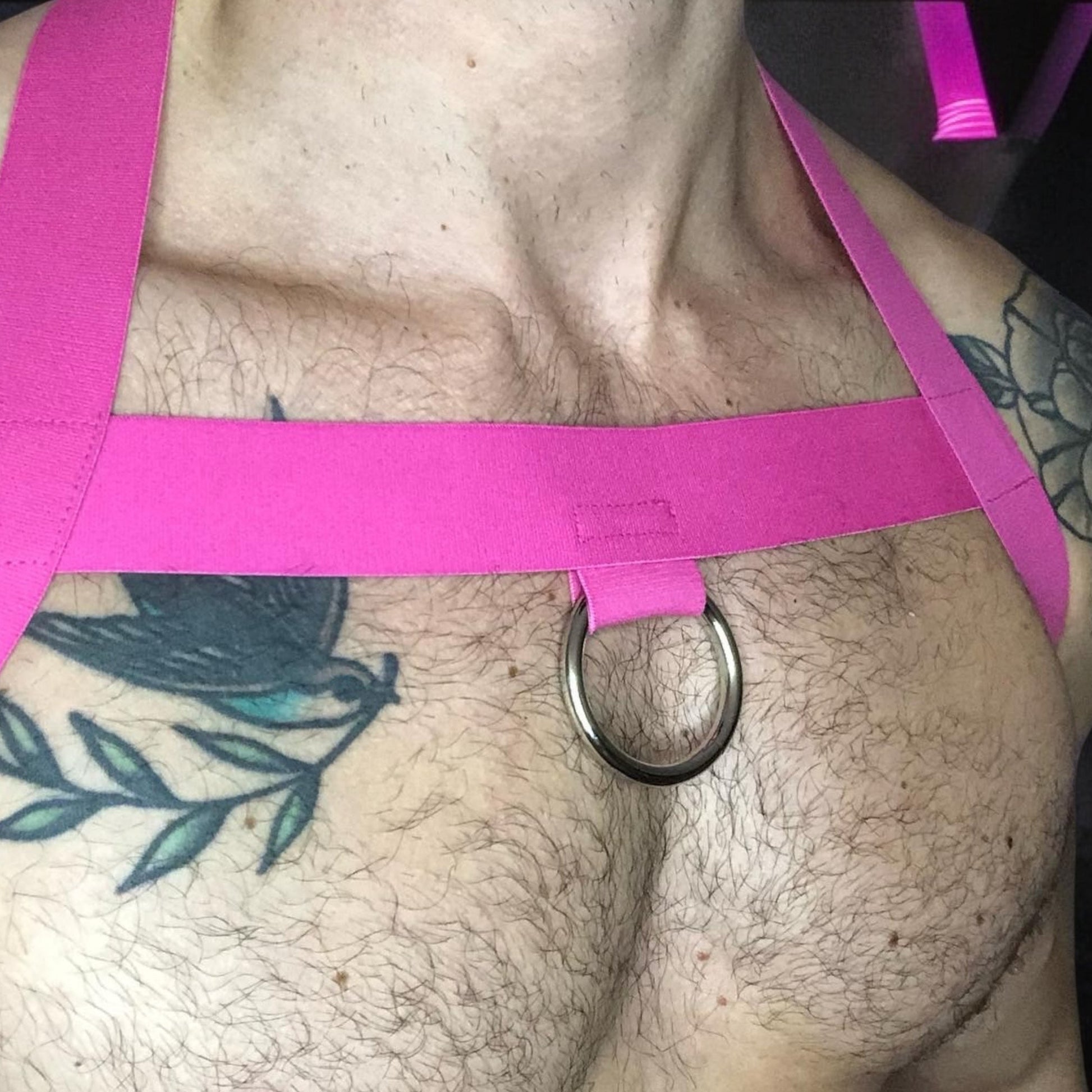 Model wearing a custom-made hot pink elastic chest harness and black mesh jockstrap by Cheeky Boy Harness. Made-to-measure men's festival and clubwear set designed for pride, circuit parties, and dance events