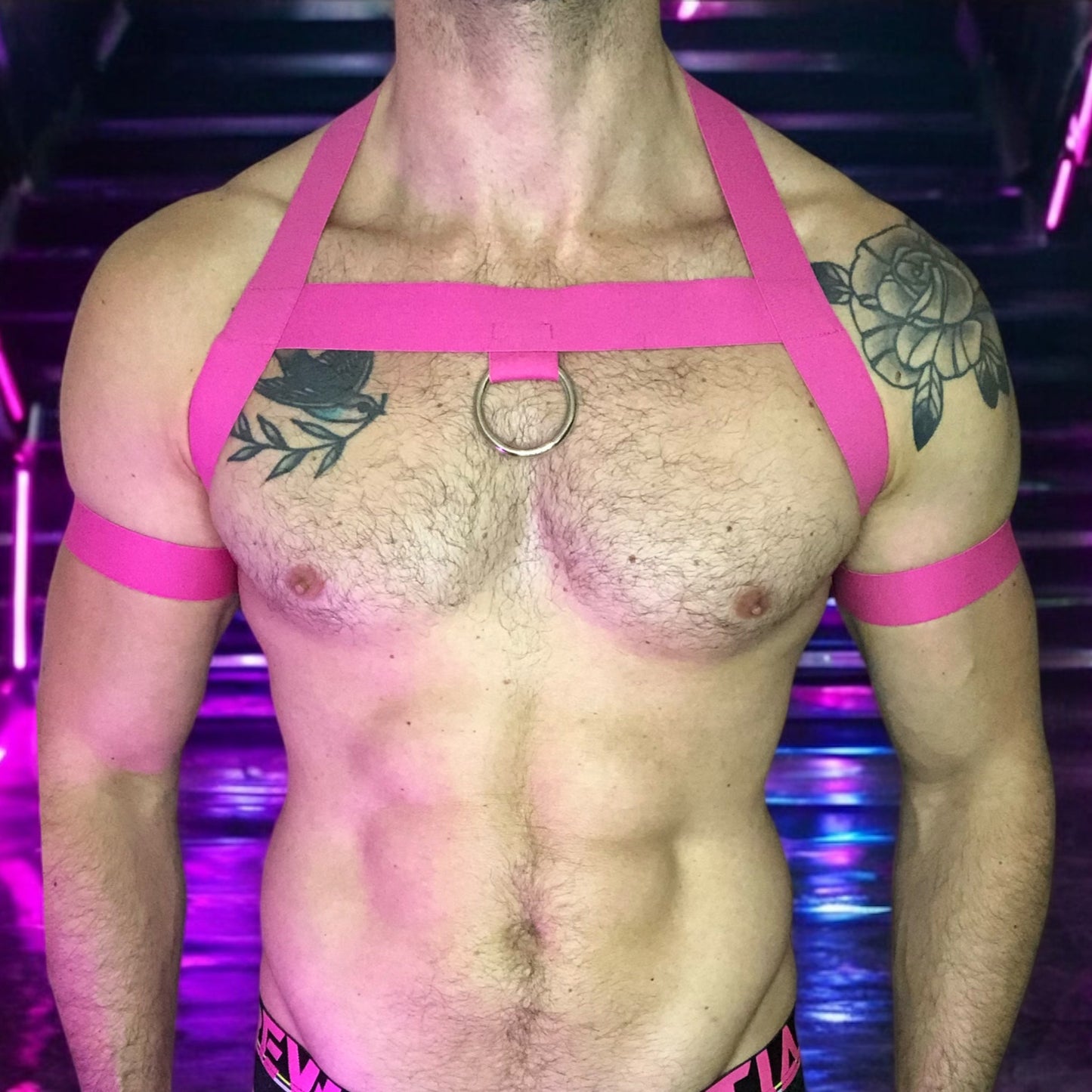 Model wearing a custom-made hot pink elastic chest harness and black mesh jockstrap by Cheeky Boy Harness. Made-to-measure men's festival and clubwear set designed for pride, circuit parties, and dance events
