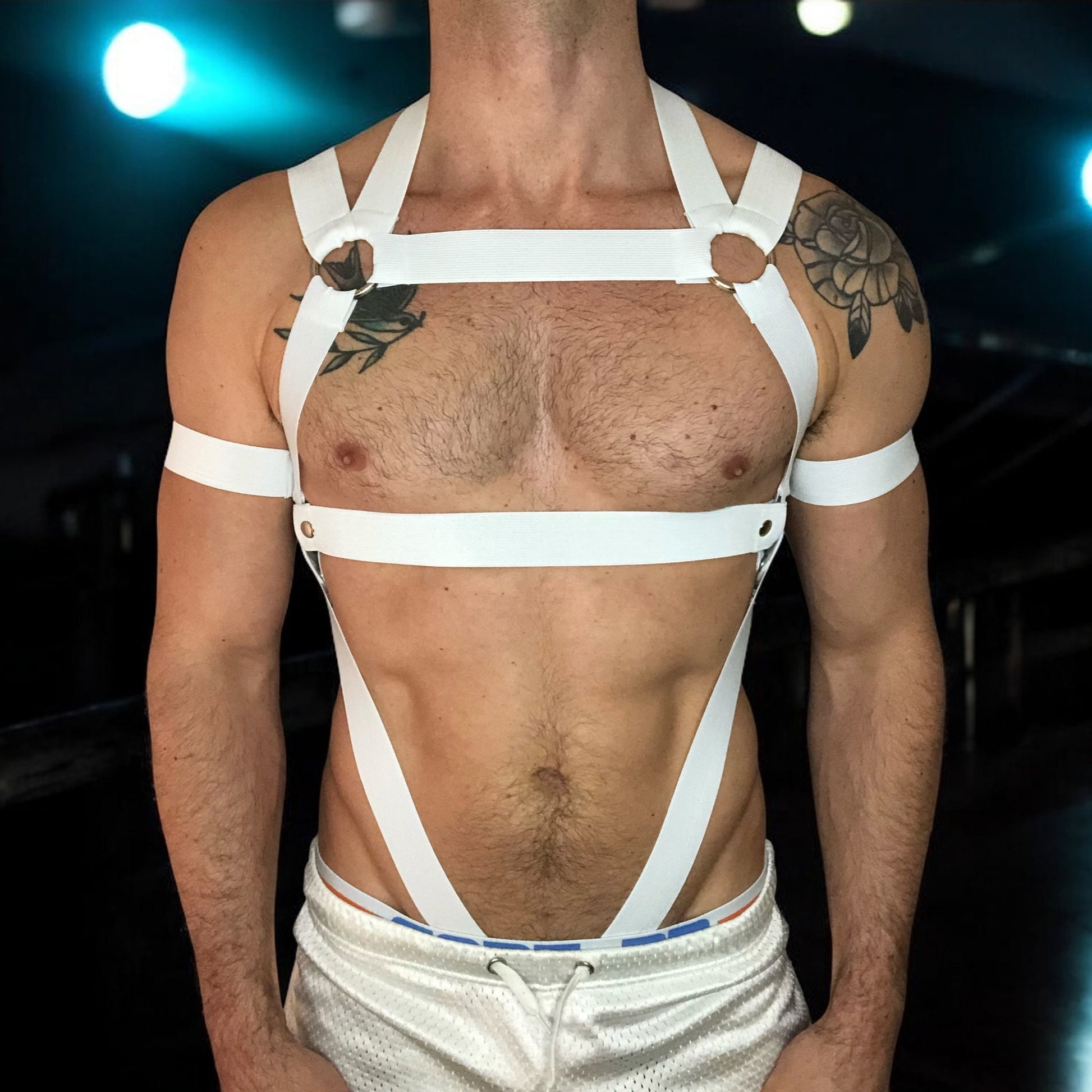Man Wearing a Made-To-Measure White Elastic Body Harness with Metal Rings and Matching Bicep Bands, Club Background, Custom Fit Design