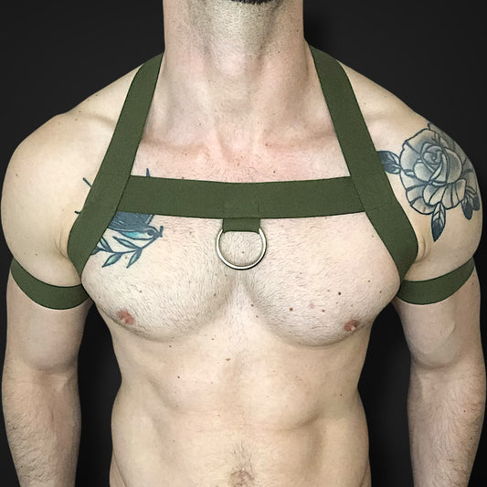 Model wearing a custom-made olive green elastic chest harness and black mesh jockstrap by Cheeky Boy Harness. Made-to-measure men's festival and clubwear set designed for pride, circuit parties, and fetish events