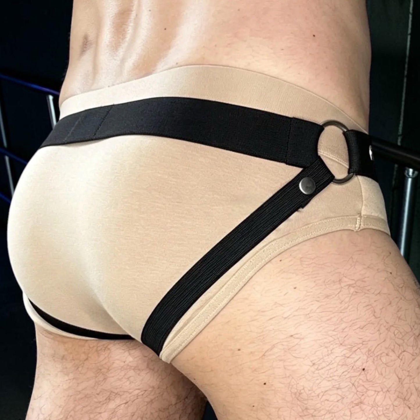 Rear three-quarter view of the standalone Jockstrap with a black waistband and back straps, worn over flesh-coloured underwear for display.