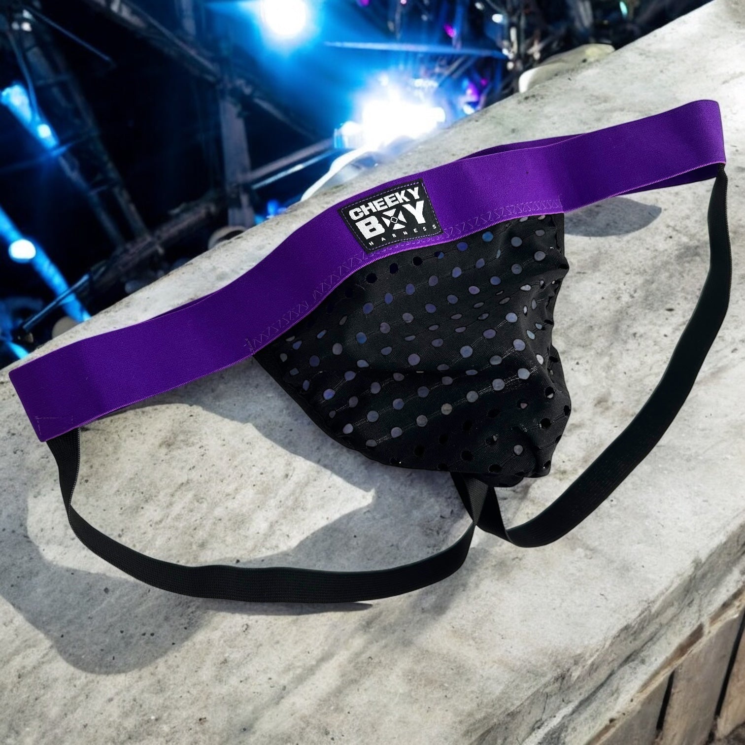 Man wearing a custom-fit purplr elastic chest and body harness with matching bicep bands, featuring metal ring details and diagonal strap design. Styled with black mesh jockstrap underwear. Handmade by Cheeky Boy Harness