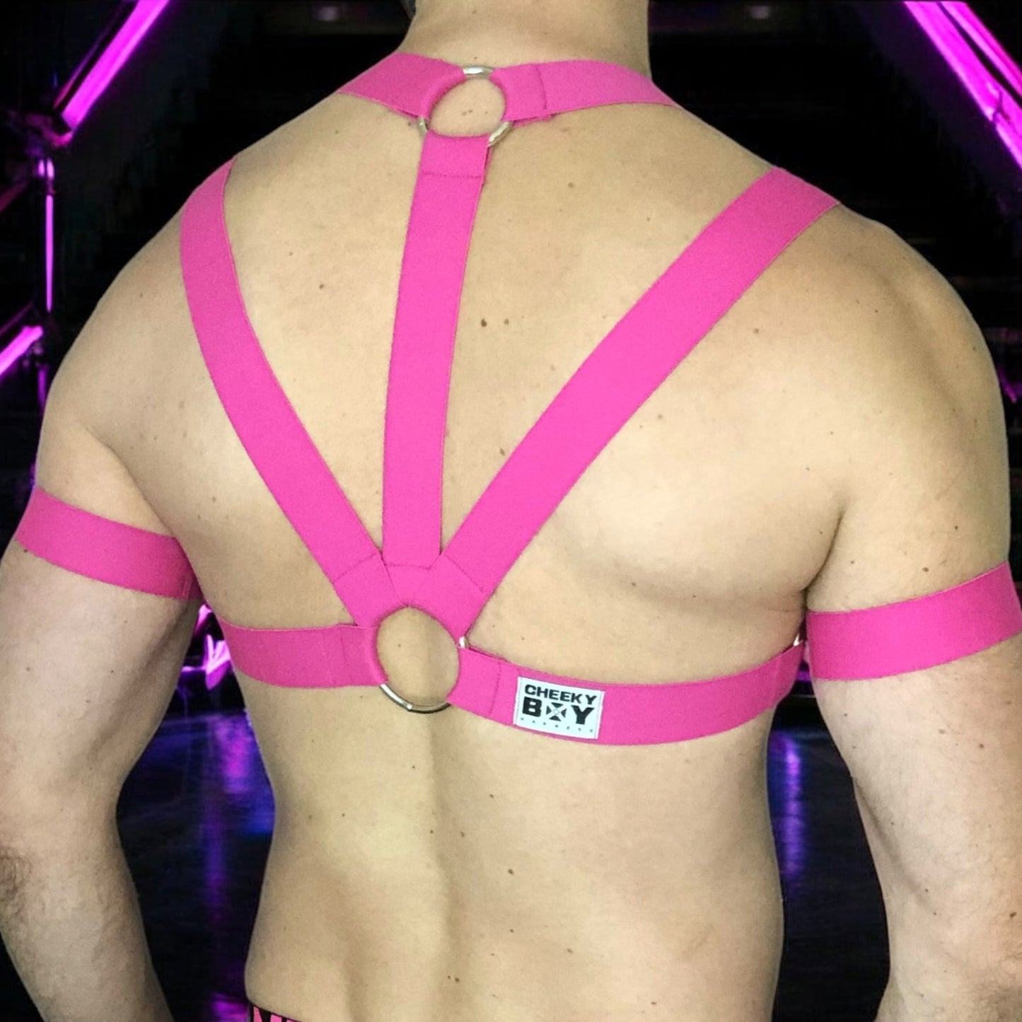 Man Wearing a Made-To-Measure Hot Pink Elastic Body Harness with Metal Rings and Matching Bicep Bands by Cheeky Boy Harness