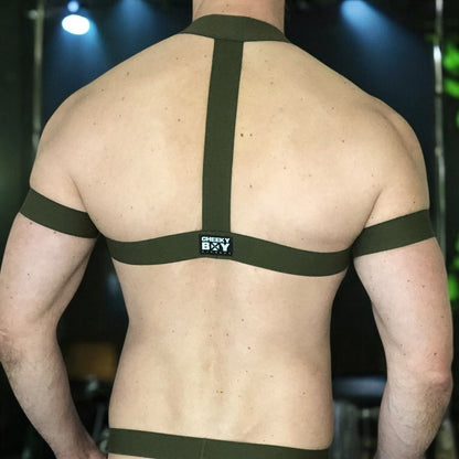 Model wearing a custom-made military green elastic chest harness and black mesh jockstrap by Cheeky Boy Harness. Made-to-measure men's festival and clubwear set designed for pride, circuit parties, and dance events