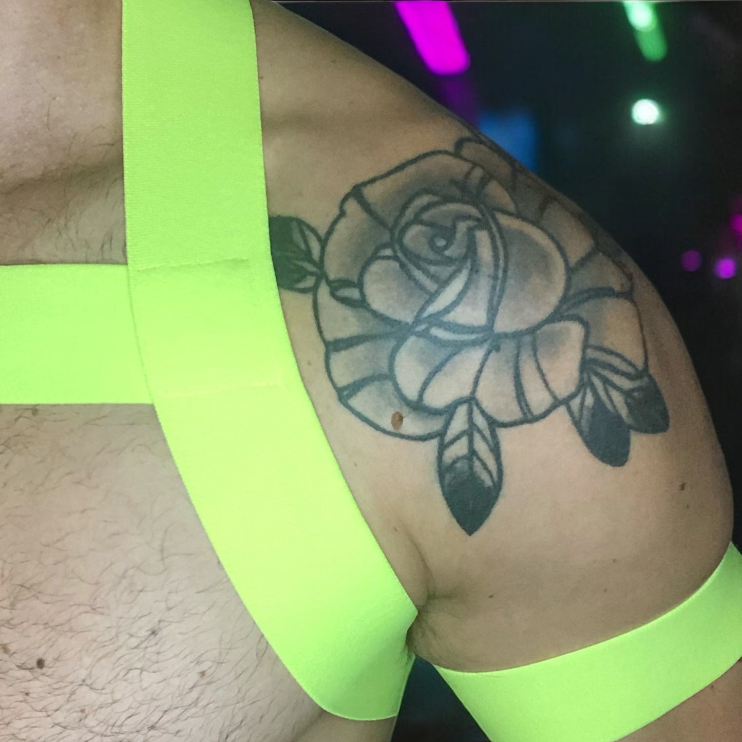 Model wearing a neon yellow chest harness with matching neon pink bicep bands and waistband jockstrap by Cheeky Boy Harness. Customisable colour options available. Perfect for festivals, clubwear, and pride events.