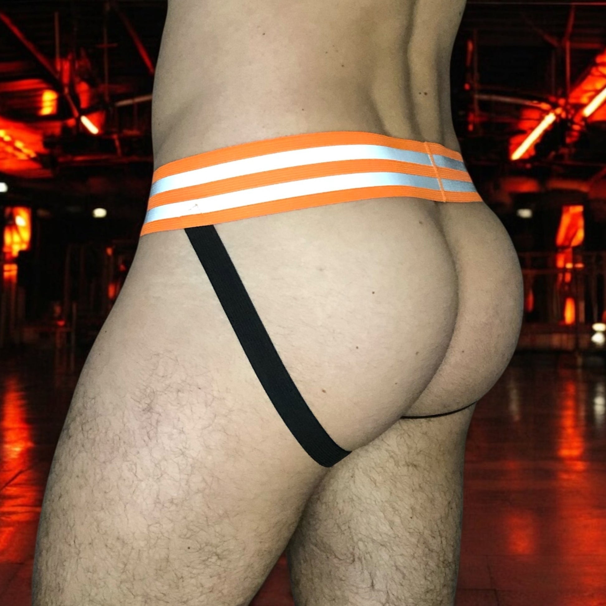 Made-to-measure men’s elastic chest harness in high-visibility neon orange with reflective detailing, glowing under blacklight. The design features double shoulder and chest straps joined by circular O-rings, with optional matching jockstrap and thigh bands—ideal for clubwear, festivals, or fetish fashion.