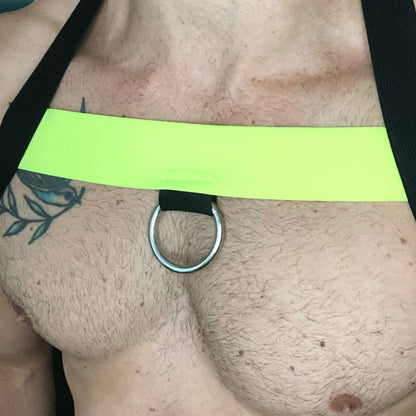 A man wearing a handmade, made-to-measure black and neon yellow elastic chest harness with matching jockstrap and bicep bands by Cheeky Boy Harness.