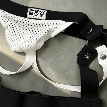Close-up comparison of the optional black and white Mesh Jockstrap pouches with Cheeky Boy Harness branding and detachable clips.