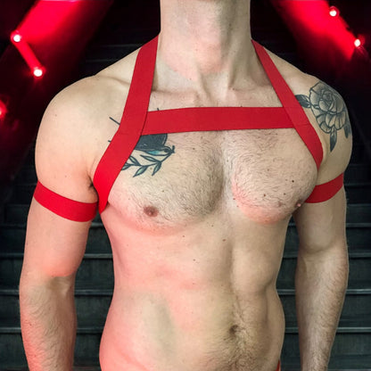 Model wearing a custom-made red elastic chest harness and black mesh jockstrap by Cheeky Boy Harness. Made-to-measure men's festival and clubwear set designed for pride, circuit parties, and dance events