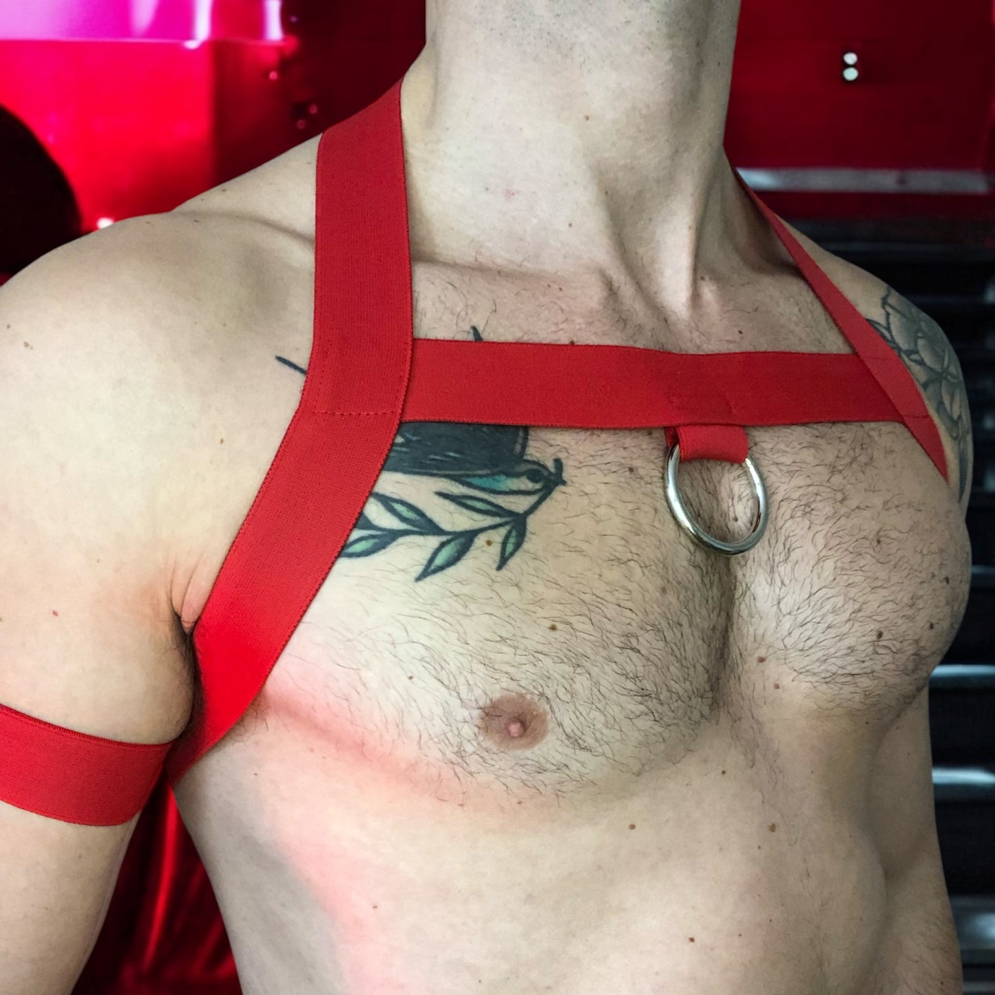Model wearing a custom-made red elastic chest harness and black mesh jockstrap by Cheeky Boy Harness. Made-to-measure men's festival and clubwear set designed for pride, circuit parties, and dance events