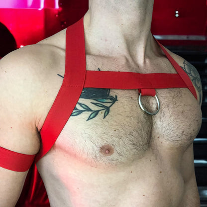 Model wearing a custom-made red elastic chest harness and black mesh jockstrap by Cheeky Boy Harness. Made-to-measure men's festival and clubwear set designed for pride, circuit parties, and dance events