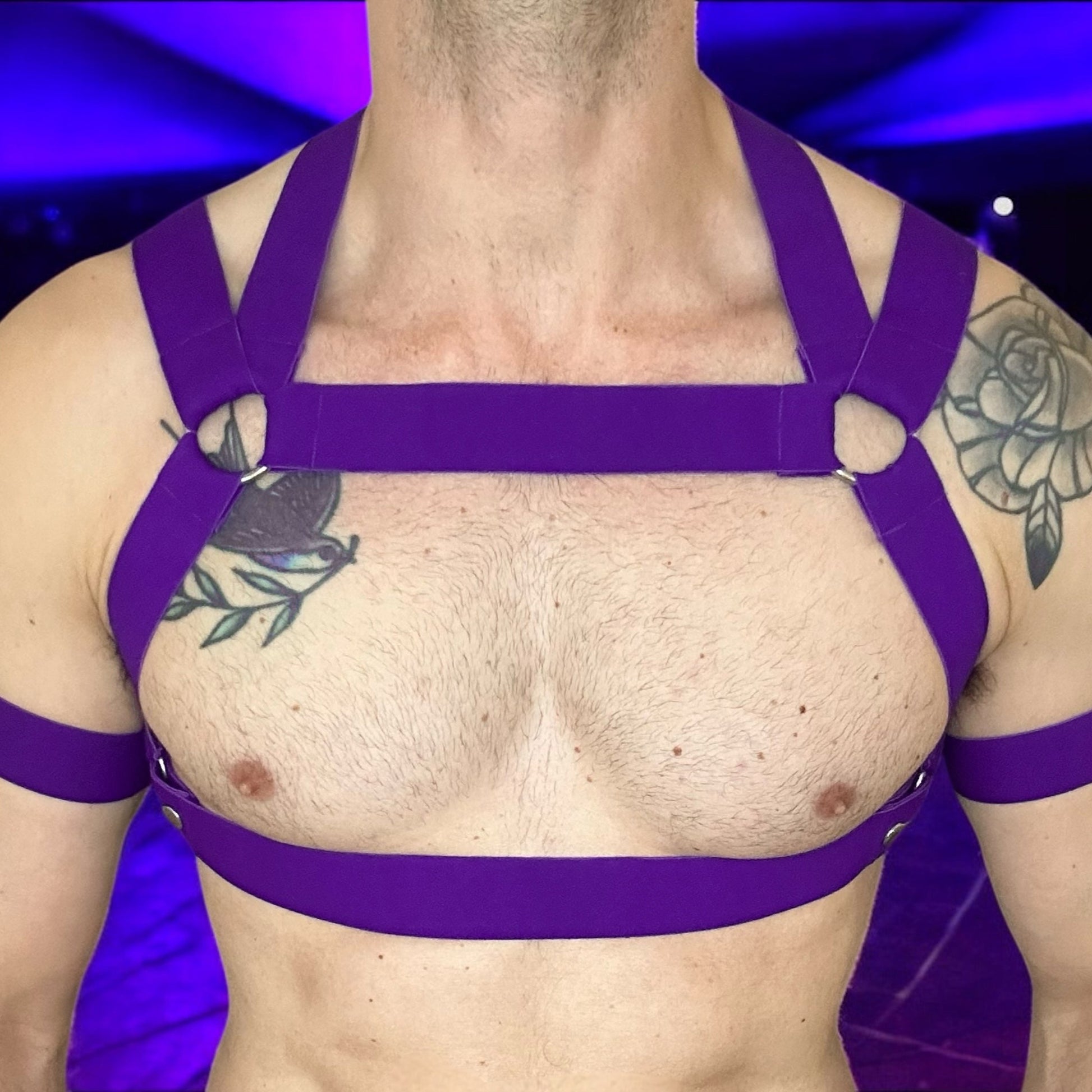 Man wearing a custom-fit purplr elastic chest and body harness with matching bicep bands, featuring metal ring details and diagonal strap design. Styled with black mesh jockstrap underwear. Handmade by Cheeky Boy Harness
